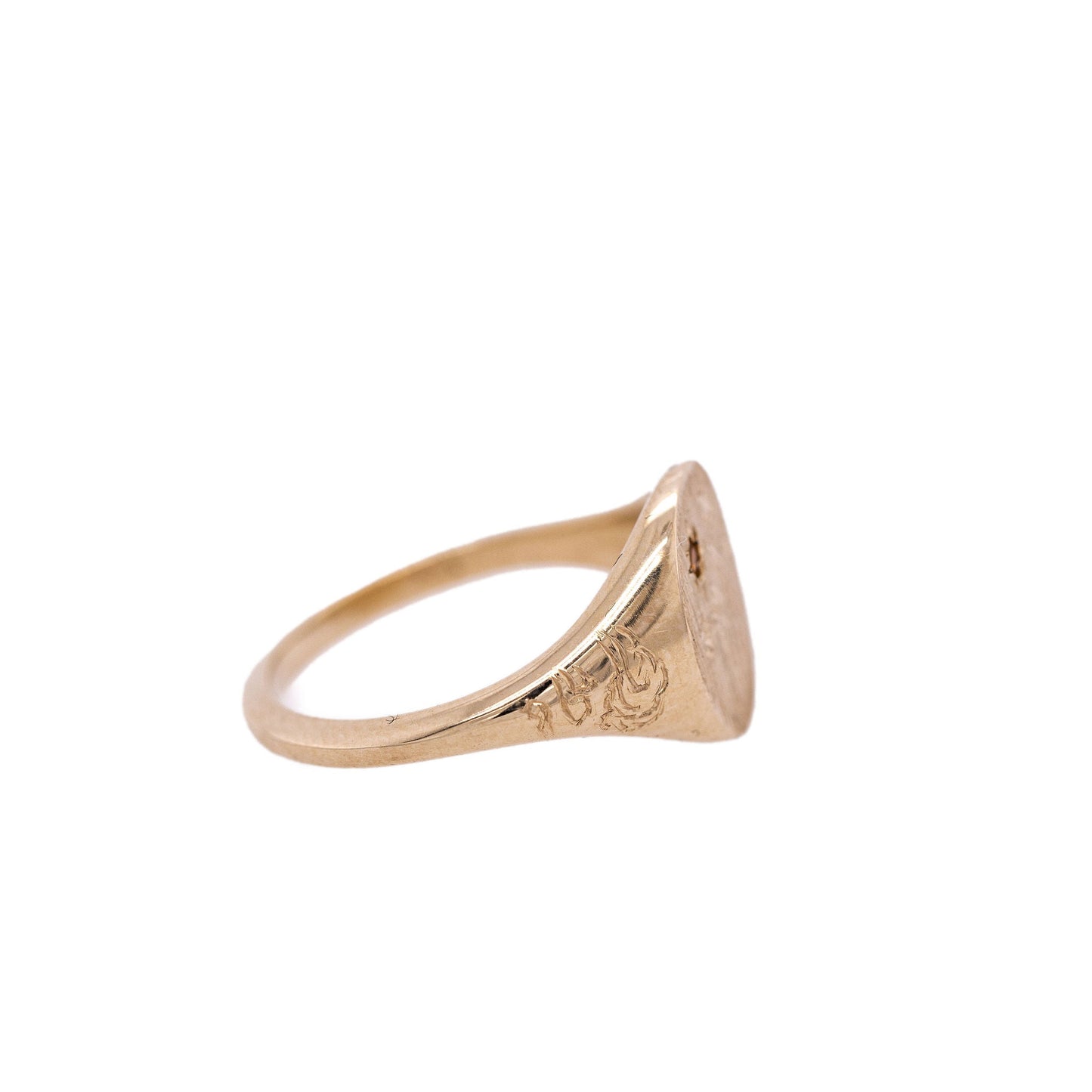 Side view of Hand-engraved gold signet ring with intricate design on a clean white background
