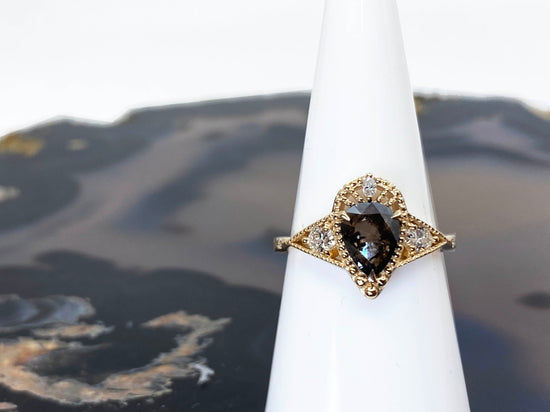 Salt and pepper diamond ring in yellow gold, photographed on a ring cone with a black agate background 