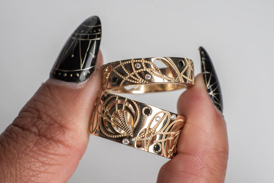 2 yellow gold cigar bands with black and white diamonds, held by a model's hand