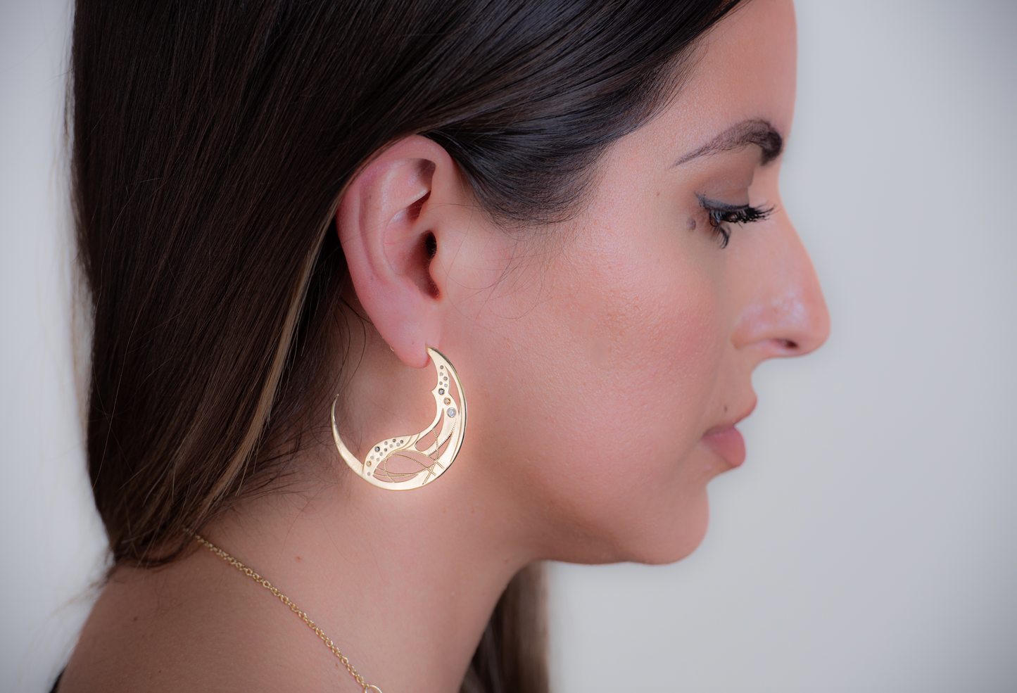 Profile shot of a model wearing yellow gold diamond hoops